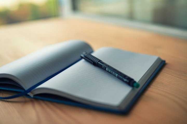 An open notebook and pen on a wooden table, an editorial scene for reading and reflection